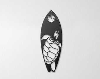 May include: Black metal wall art featuring a turtle on a surfboard with a seashell. The art is hanging on a white wall above a wooden headboard.