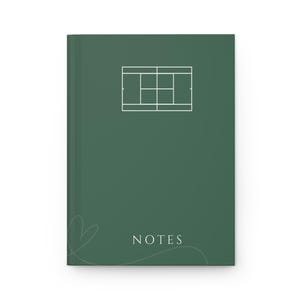 Puede incluir: Un cuaderno verde oscuro con un contorno blanco de una cancha de tenis y la palabra "NOTES" en blanco. El cuaderno tiene un simple dibujo de corazón blanco en la esquina inferior izquierda.