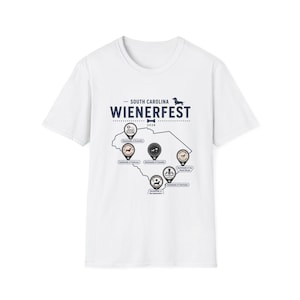 May include: A white short-sleeve t-shirt featuring a graphic of the state of South Carolina with the text "SOUTH CAROLINA WIENERFEST 2026". The design includes map pins marking various locations with dachshund illustrations and city names.