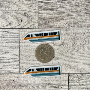 May include: Two white and blue model trains with orange stripes. The trains are on a woodgrain background.