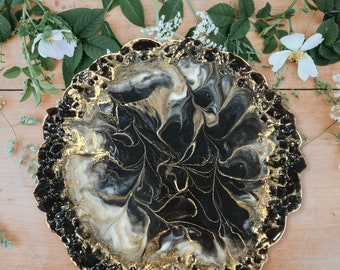 May include: A black and gold resin tray with a marbled design. The tray has a rough, textured edge.