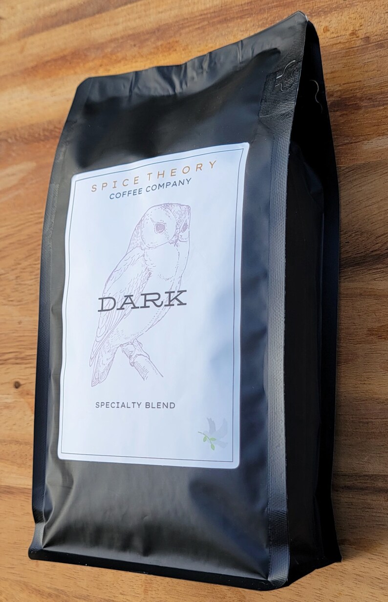May include: Black coffee bag with a white label featuring a drawing of an owl and the text "Spice Theory Coffee Company" and "Dark Specialty Blend".