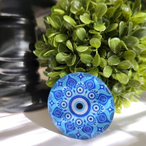 May include: A blue and white ceramic coaster with a mandala design and a blue evil eye in the center.