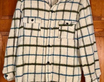 May include: Cream-colored, button-down shirt with a plaid pattern in shades of green and blue. The shirt has two chest pockets and black buttons. The fabric appears to be a thick, textured material.