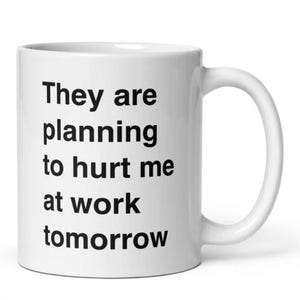 May include: White ceramic mug with a curved handle. The mug features black text that reads: "They are planning to hurt me at work tomorrow."