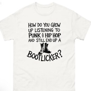 Puede incluir: Camiseta blanca con texto negro y un gráfico de botas. El texto dice: "¿CÓMO CRECES ESCUCHANDO PUNK & HIP HOP Y TERMINAS SIENDO UN BOOTLICKER?"