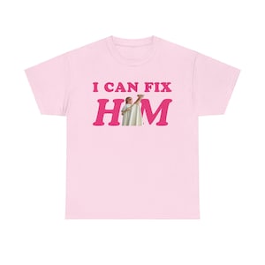May include: Pink t-shirt with the text "I can fix him" in pink letters. A photo of a man holding a camel is in the middle of the text.