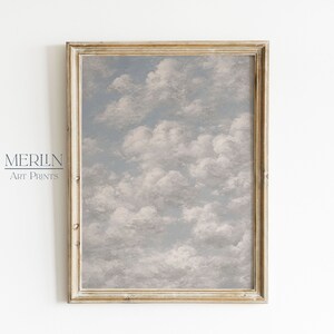 Peut inclure: Une impression d'art encadrée représentant un ciel nuageux. L'œuvre d'art montre un ciel bleu clair rempli de nuages blancs et duveteux. Elle est présentée dans un cadre en bois doré vieilli. Le texte "MERILN Art Prints" est visible en bas à gauche.