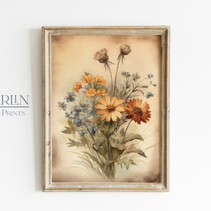 K&ouml;nnte beinhalten: Ein gerahmtes Aquarellbild eines Blumenstrau&szlig;es in Orange-, Gelb- und Blaut&ouml;nen. Die Blumen sind in einer Vase arrangiert und vor einem beigefarbenen Hintergrund platziert.