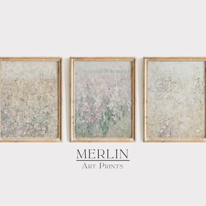 May include: Three framed art prints with a watercolor-like style depicting a field of wildflowers in shades of white, pink, and green. The prints are in simple, light wood frames.