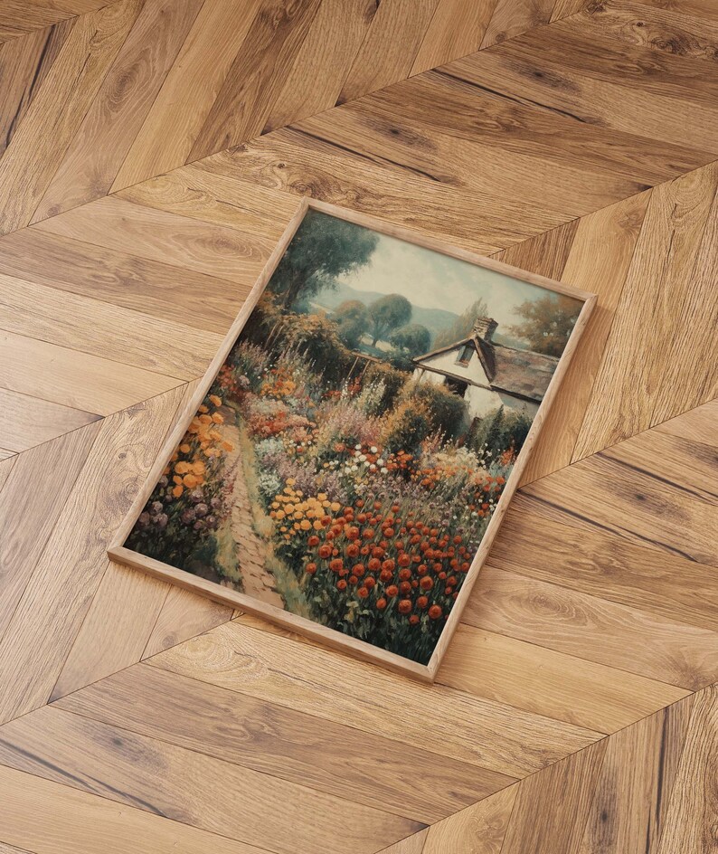 May include: A framed painting of a cottage with a garden in full bloom. The garden is filled with a variety of flowers in shades of red, yellow, and purple. The cottage is white with a brown roof and is surrounded by lush greenery.