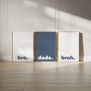May include: Three framed prints with white backgrounds and gold frames. The prints have the words "bro.", "dude.", and "bruh." in bold, dark blue letters.