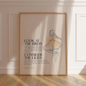 Puede incluir: Impresión enmarcada con una ilustración de un pájaro y una flor de lirio. La obra de arte incluye el texto "MIRAD LAS AVES" y "CONSIDERAD LOS LIRIOS" con una referencia bíblica. El fondo es de color beige suave.