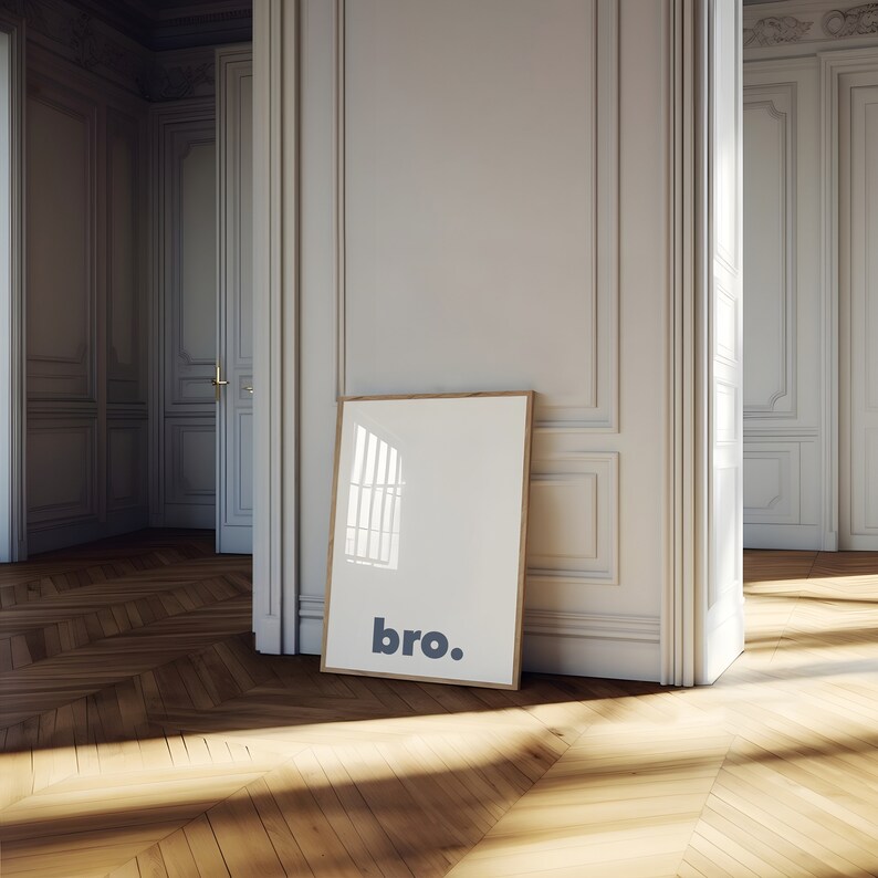 May include: A framed print with the word "bro." printed in blue on a white background. The frame is light wood and the print is leaning against a white wall.