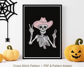 Könnte beinhalten: Kreuzstichmuster eines Skeletts, das einen rosafarbenen Cowboyhut trägt und mit beiden Händen das Friedenszeichen macht. Der Hintergrund ist schwarz.