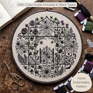 May include: A circular embroidery hoop containing a hand embroidery pattern on beige fabric. The design features a black wrought iron gate, spiderwebs, spiders, purple roses, green foliage, and a bat. Text reads: DMC Color Guide Included & Stitch Types.