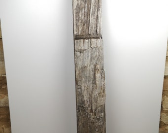 Può includere: Una trave di legno grigia e consumata con una superficie ruvida e testurizzata. La trave è lunga circa 1,5 metri e ha un aspetto naturale e rustico.