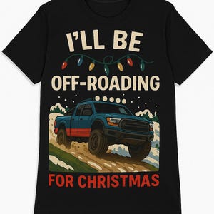 May include: Black t-shirt with a graphic of a blue and red off-road truck driving on a snowy path. The text reads "I'll be off-roading for Christmas" with Christmas lights above the truck.