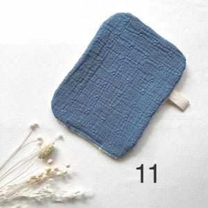 May include: A blue rectangular baby washcloth with a floral pattern and a white trim. The washcloth has a cream-colored strap on the side. The number "11" is printed in black on the bottom right corner.