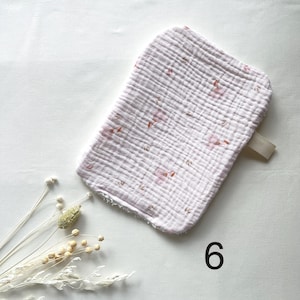 May include: A light pink, rectangular baby washcloth with a floral pattern. The washcloth has a textured, crinkled appearance and a small loop on one end. The number "6" is printed in black on the bottom right.