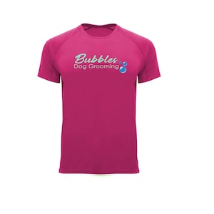 May include: A magenta short-sleeved t-shirt with the text "Bubbles Dog Grooming" in a teal script font. The design includes teal bubbles. The shirt is made of a smooth, likely athletic material.