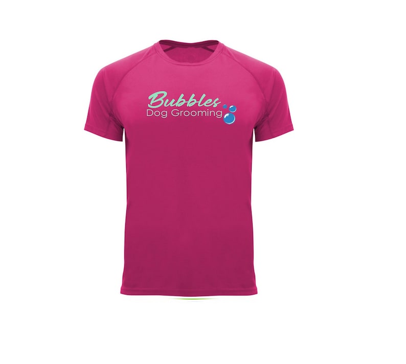 May include: A magenta short-sleeved t-shirt with the text "Bubbles Dog Grooming" in a teal script font. The design includes teal bubbles. The shirt is made of a smooth, likely athletic material.