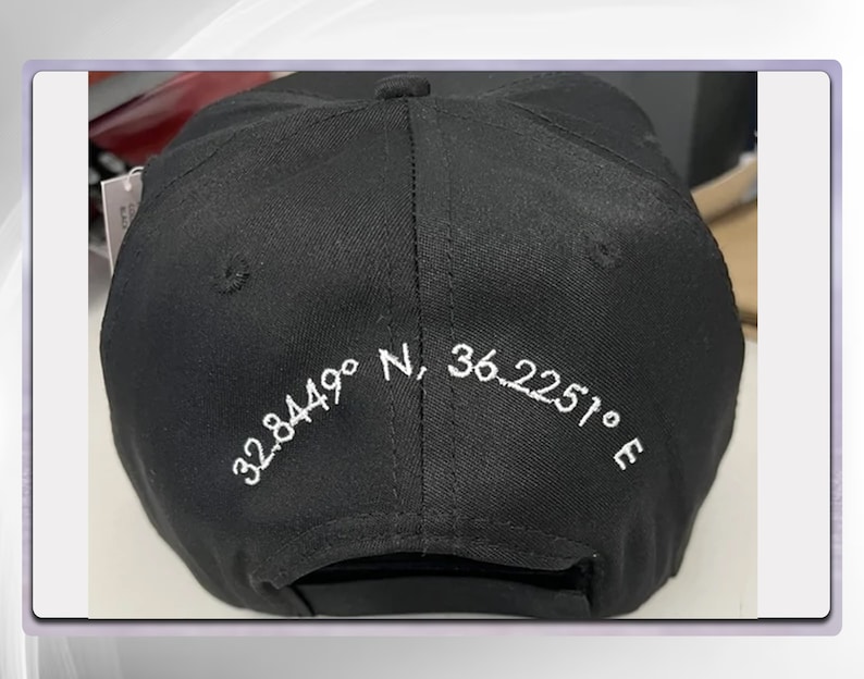 May include: Black baseball cap with white embroidered coordinates: 32.8449&deg; N, 36.2251&deg; E.