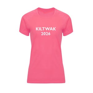 Op de afbeelding: Een roze T-shirt met korte mouwen en de witte tekst "KILTWAK 2026" op de voorkant. Het shirt heeft een ronde hals en een getailleerde pasvorm. De stof lijkt een lichtgewicht, sportief materiaal te zijn.