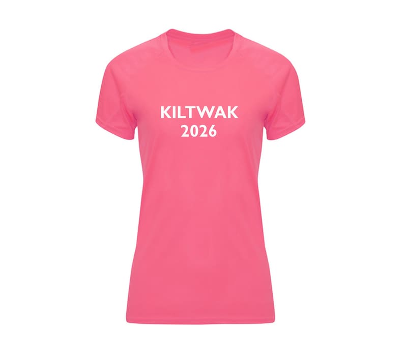 Op de afbeelding: Een roze T-shirt met korte mouwen en de witte tekst "KILTWAK 2026" op de voorkant. Het shirt heeft een ronde hals en een getailleerde pasvorm. De stof lijkt een lichtgewicht, sportief materiaal te zijn.