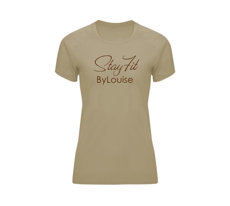 Op de afbeelding: Een beige T-shirt met korte mouwen met de tekst "Stay Fit ByLouise" in bruine letters. Het shirt heeft een ronde hals en een eenvoudig ontwerp, geschikt voor fitness of casual wear.