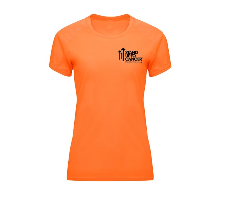 Op de afbeelding: Fel oranje T-shirt met korte mouwen en een ronde hals. Het shirt heeft het zwarte "Stand Up To Cancer" logo op de linkerborst. Gemaakt van lichtgewicht, ademend materiaal.