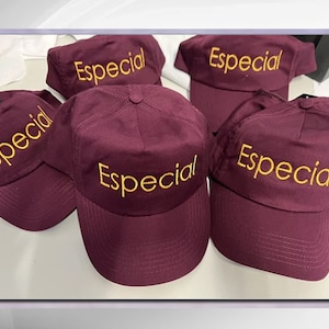 May include: Five maroon baseball caps with the word "Especial" embroidered in yellow on the front.