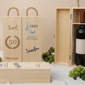 Peut inclure: Coffrets à vin en bois avec poignées en corde. L'un est ouvert, montrant une bouteille de vin. D'autres sont fermés, avec du texte et des motifs, dont "Karl", "1985" et "50". Des grappes de raisin sont disposées autour.