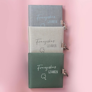 Op de afbeelding: Drie grijze, beige en groene, met stof beklede dagboeken met sloten en de tekst "Franziskas Gedanken" op elk.