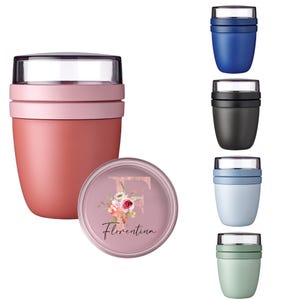 Könnte beinhalten: Isolierte Lebensmittelbehälter in verschiedenen Farben, darunter Rosa, Blau, Schwarz und Grün. Der Hauptbehälter ist rosa mit einem transparenten Deckel. Ein passender Deckel zeigt ein Blumendesign und den Namen "Florentina".