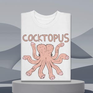 Puede incluir: Camiseta blanca con un diseño de pulpo de dibujos animados en rosa. La palabra "COCKTOPUS" está impresa encima del pulpo en letras rosas. La camiseta se muestra sobre un pedestal blanco sobre un fondo gris.