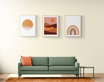 May include: A green sofa with a burnt orange throw pillow sits in front of a wall with three framed abstract art prints. The prints feature a yellow circle, a sunset landscape, and a rainbow. The sofa is on a brown rug in a room with a light wood floor.