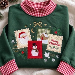 Puede incluir: Una sudadera verde oscuro de manga larga con cuello y puños de cuadros vichy rojos y blancos. El frente presenta diseños bordados de sellos postales con Santa Claus, una casa y un muñeco de nieve con el texto Merry Christmas.