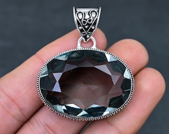 May include: A silver pendant with a large, faceted, oval-shaped, dark gray gemstone. The pendant has a detailed, ornate bail.
