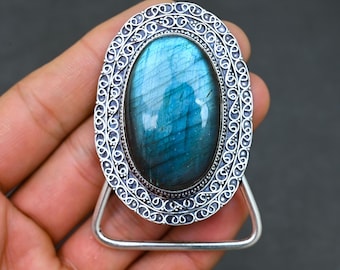 May include: A silver oval pendant with a blue labradorite gemstone set in a filigree design. The pendant is attached to a silver chain.