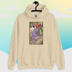 May include: A beige hoodie with a front graphic of a purple tiger in a traditional Asian art style. The tiger is depicted with yellow eyes and white whiskers, set against a backdrop of a tree, a red sun, and Korean text.