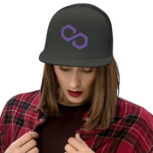 May include: A black trucker hat with a purple polygon logo embroidered on the front. The hat has a mesh back and a flat brim. The hat is worn by a person wearing a red and black plaid shirt.