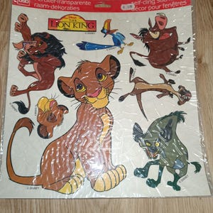 Op de afbeelding: Een vel met The Lion King raamstickers met Simba, Nala, Pumbaa, Timon, Zazu en Scar. De stickers zijn transparant en zelfklevend.
