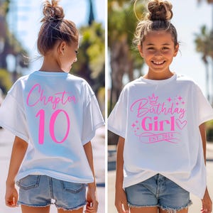 Könnte beinhalten: Weißes T-Shirt mit rosa Schrift. Die Vorderseite des Shirts lautet "Birthday Girl" mit einer Krone, Sternen und einem Herzen. Die Rückseite des Shirts lautet "Chapter 10".