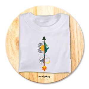 Könnte beinhalten: Weißes T-Shirt mit einem grafischen Design eines stilisierten Pfeils mit einem Berg, einer Sonne, einer Welle und einem Mond. Der Text "Printrebel" ist auf der Unterseite des Shirts gedruckt.