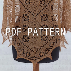 Peut inclure: Un châle tricoté marron clair présentant un motif en dentelle complexe avec de petites boules et un ourlet pointu. Le texte PDF PATTERN est superposé en lettres capitales blanches au centre du vêtement, présenté sur un mannequin.