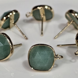May include: Six pairs of gold-tone earring posts with green gemstone tops. The gemstones are square-shaped and have a faceted design.