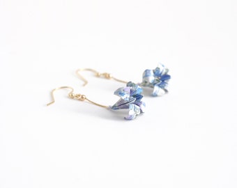 May include: A pair of gold dangle earrings with blue and white origami flower charms.