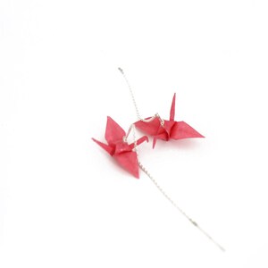 May include: A pair of pink origami crane earrings with silver chains.
