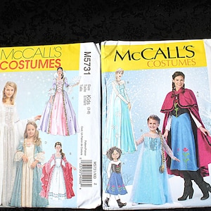 May include: Two McCall's Costumes sewing pattern envelopes. One features a white and pink gown, the other a blue dress and red cape. Both are for kids' sizes, with the M5731 pattern for sizes 3-8 and the M7000 pattern for sizes 3-14.
